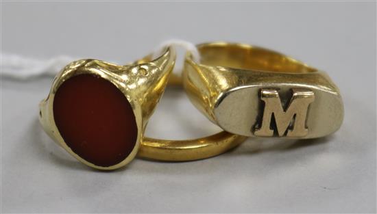 A 22ct gold wedding band and two yellow metal rings including one set with carnelian stone.